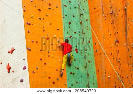 The young man on rock wall in sport center outdoor
