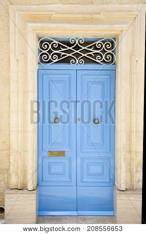 Light blue wooden entrance door with ornated sign and knocker