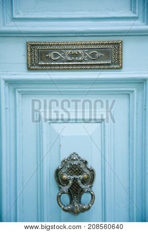 Light blue wooden entrance door with ornated sign and knocker