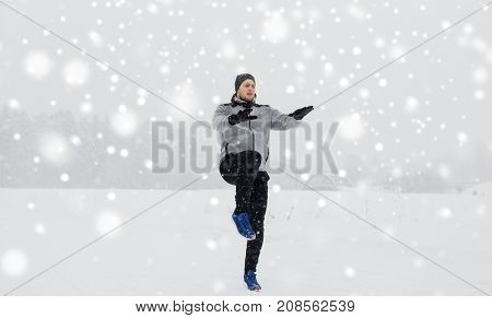 fitness, sport, people, exercising and healthy lifestyle concept - young man exercising and warmig up in winter outdoors