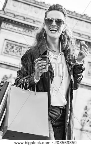 Stylish autumn in Paris. smiling trendy woman in sunglasses with shopping bags in Paris France having coffee and macaroon