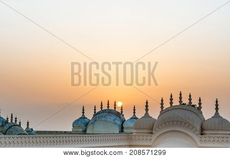 Domes and spires of the Nahargarh fort in Jaipur shot against the setting sun. The hindu Rajput architecture is complemented perfectly by the orange hue of the sun