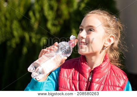 Beautiful girl drinking water after jogging in outdoor. A  beautiful girl is drinking water the hot sun in the park. Healthily concept. Healthy lifestyle concept. copy space. Portrait  beautiful girl