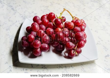 A Studio Photograph of a Bunch of 'Flame' Variety (Vitis Vinifera) Grapes on a Serving Plate