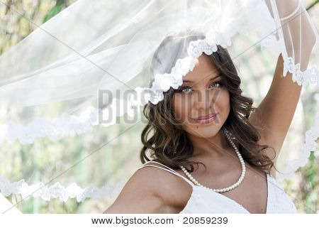 Jeune mariée mignonne posant avec un voile