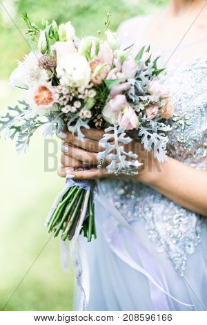 Bride holding wedding bouquet outdoors, daylight rustic style
