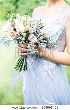Bride holding wedding bouquet outdoors, daylight rustic style