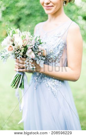 Bride holding wedding bouquet outdoors, daylight rustic style