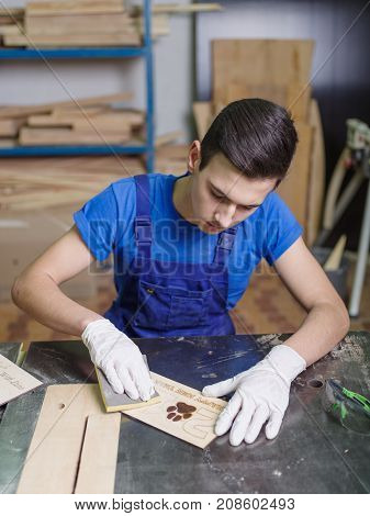 A carved plate on which the patterns and inscriptions are burned out that the master in blue overalls handle with a special tool