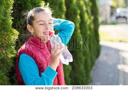 Beautiful girl is drinking water the hot sun in the park. Healthily concept. Healthy lifestyle concept. copy space. Portrait happy smiles beautiful girl . elightful Portrait smiles girl.