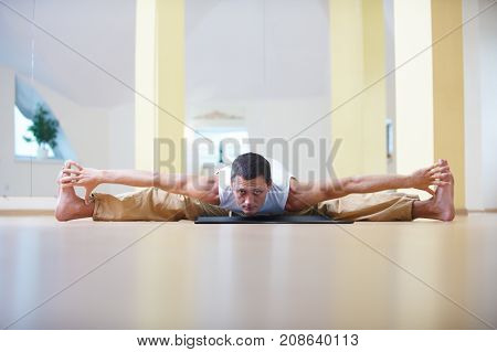 A young strong man doing yoga exercises -Samakonasana Straight angle pose in the yoga studio.