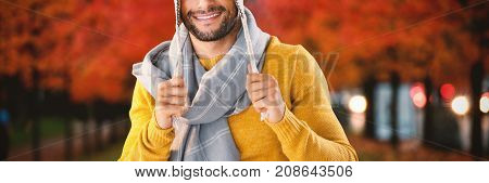Portrait of smiling man holding wooly hat against leaves on field amidst trees