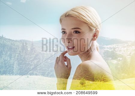 Cheerful emotions. Close up of wonderful girl looking away while touching her face with a finger