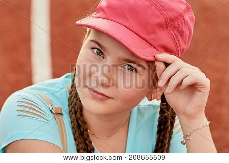 A young bright girl loves sports.sporty girl in the baseball cap pink.Closeup portrait of a teenage girl.
