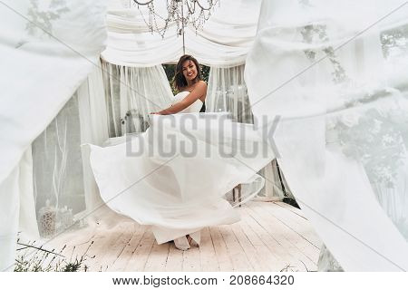 Happy to be married. Full length of attractive young woman in wedding dress smiling while dancing in the wedding pavilion outdoors