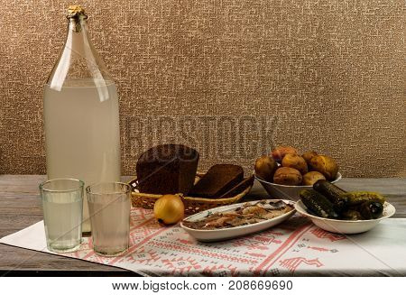 Ukrainian National Drink And Snack. The Big Bottle And Glass Of Moonshine On The Old Wooden Table