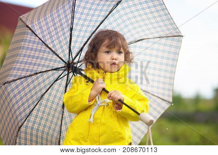 Toddler Girl Wearing Yellow Waterproof Coat With Checkered Umrella