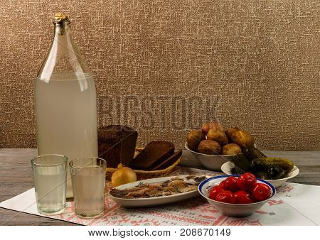 Ukrainian National Drink And Snack. The Big Bottle And Glass Of Moonshine On The Old Wooden Table