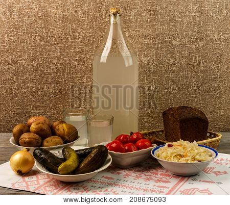 Ukrainian National Drink And Snack. The Big Bottle And Glass Of Moonshine On The Old Wooden Table