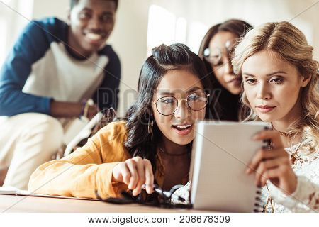 group of excited mutiethnic students looking at notebook