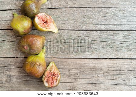 Ripe green and brown figs located on the left on the wooden table