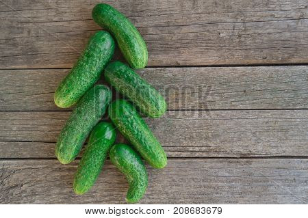 Green cucumbersl are arranged in the form of a Christmas tree on the wooden table