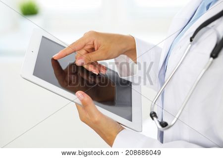 Woman doctor using tablet computer while standing straight in hospital.