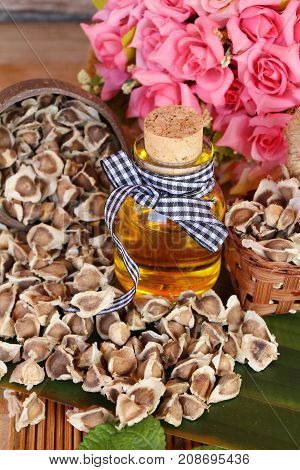 Moringa oleifera oil and seeds on wood background
