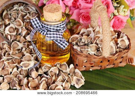 Moringa oleifera oil and seeds on wood background