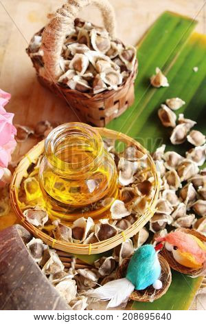Moringa oleifera oil and seeds on wood background