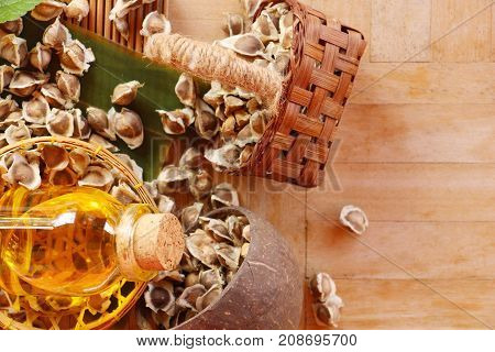 Moringa oleifera oil and seeds on wood background