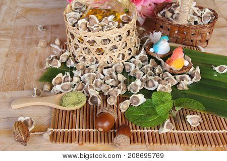 Moringa oleifera oil and seeds on wood background