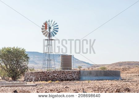 A farm scene with a water-pumping windmill and dam at Bergsig a small village in the Kunene Region of Namibia