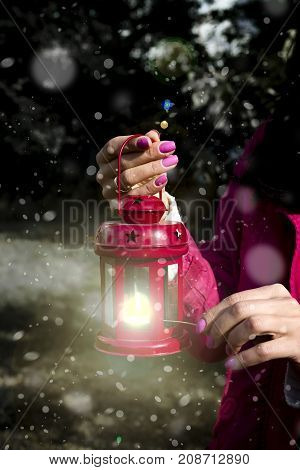 Woman hand with latern. Christmas background with snow in outdoor
