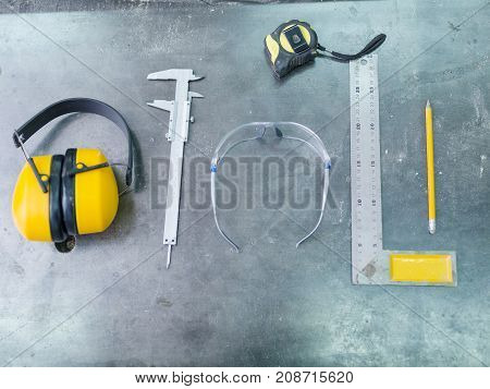 Tools of the carpenter close-up on a gray background of the table calliper, roulette, glasses, corner, pencil