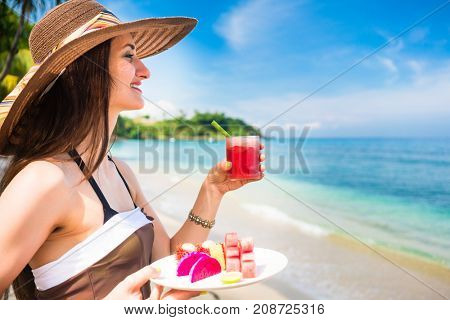 woman tourist at tropical beach eating fruit like water melon, pineapple and barbary fig for breakfast