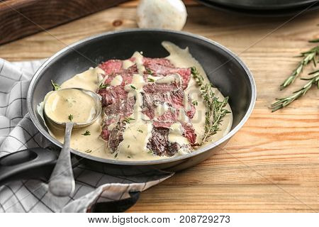 Frying pan with steak Diane on table