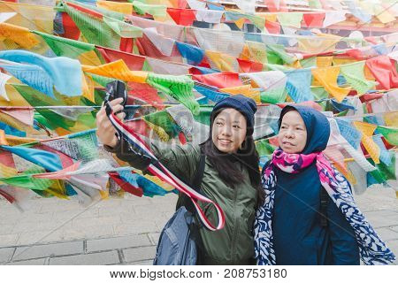 Mother and daughter tourists are traveling and selfie in Little Potala Palace Lamasery The famous temple in shangri-la yunnan china