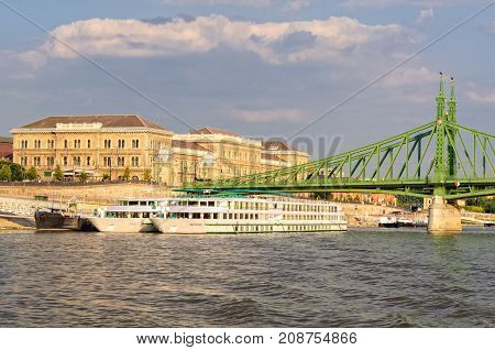 Danube river cruise ships at the Liberty Bridge and Corvinus University of Budapest, Hungary - 18 July 2013