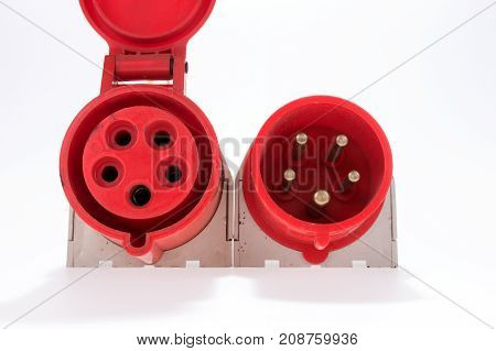 Red and white three-phase plug and socket with a lid lying beside isolated on white