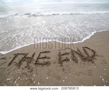 The End Text Written On The Sand And The Wave That Is Deleting T