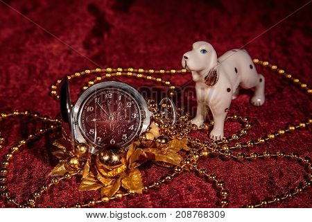 Christmas still life with metal pocket watch and porcelain dog on Burgundy background