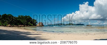 Landscape of a tropical beach with coral reef and cloudy sky Anse Severe La Digue Seychelles