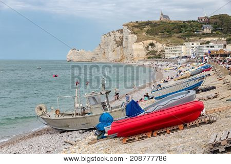 ETRETAT, FRANCE - AUGUST 25, 2017: Fishing boats and seaside visitors at the beach near the cliffs of Etretat in Normandie, France