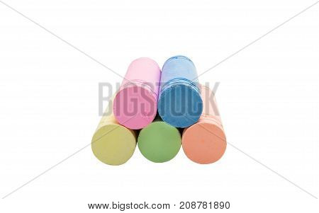 Sticks of pastel colored chalk casting shadow on white background.