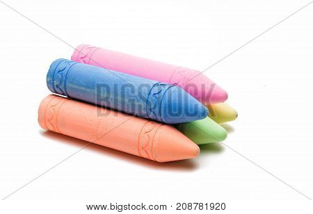 Sticks of pastel colored chalk casting shadow on white background.
