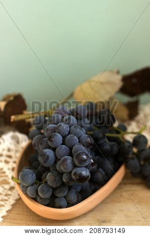Grapes in a clay plate on a wooden background. Rustic style selective focus. Vertical.