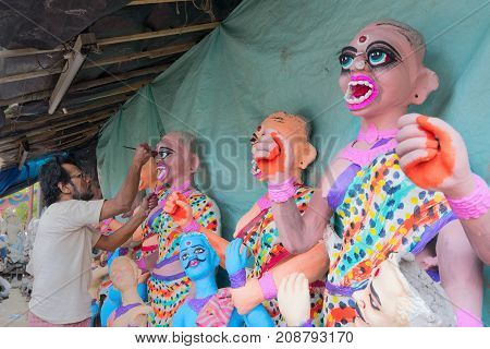 KUMARTULI KOLKATA INDIA - OCTOBER 10 2014 - Artist preparing clay idols of female demons to be used during Kali Puja worshipping of Goddess Kali Hindu festival of Deepavali or Diwali.