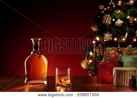 close up view  of glass with whiskey  and bottle aside on color back.