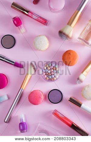 Make up products and macaroons pattern on pink background